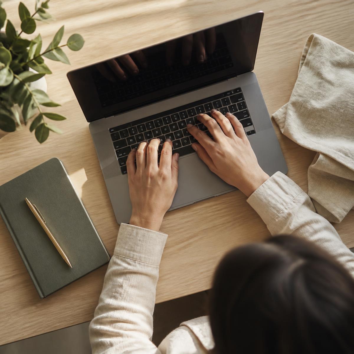 Person som arbetar vid en laptop på ett träbord